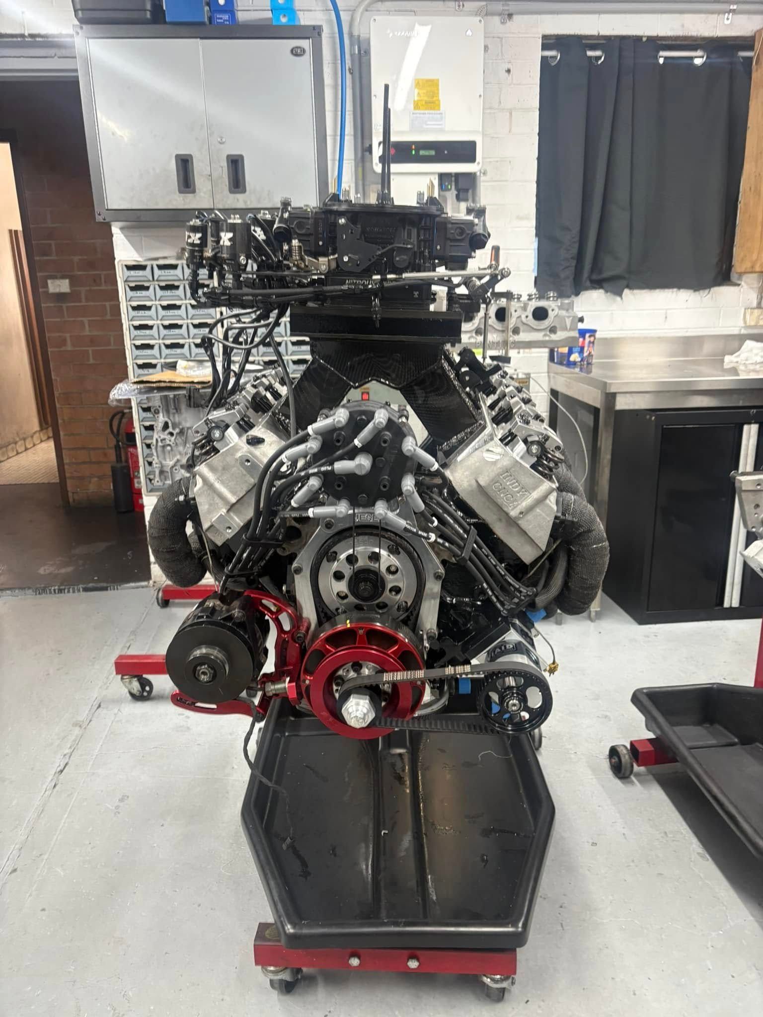 A large engine is sitting on a stand in a garage.