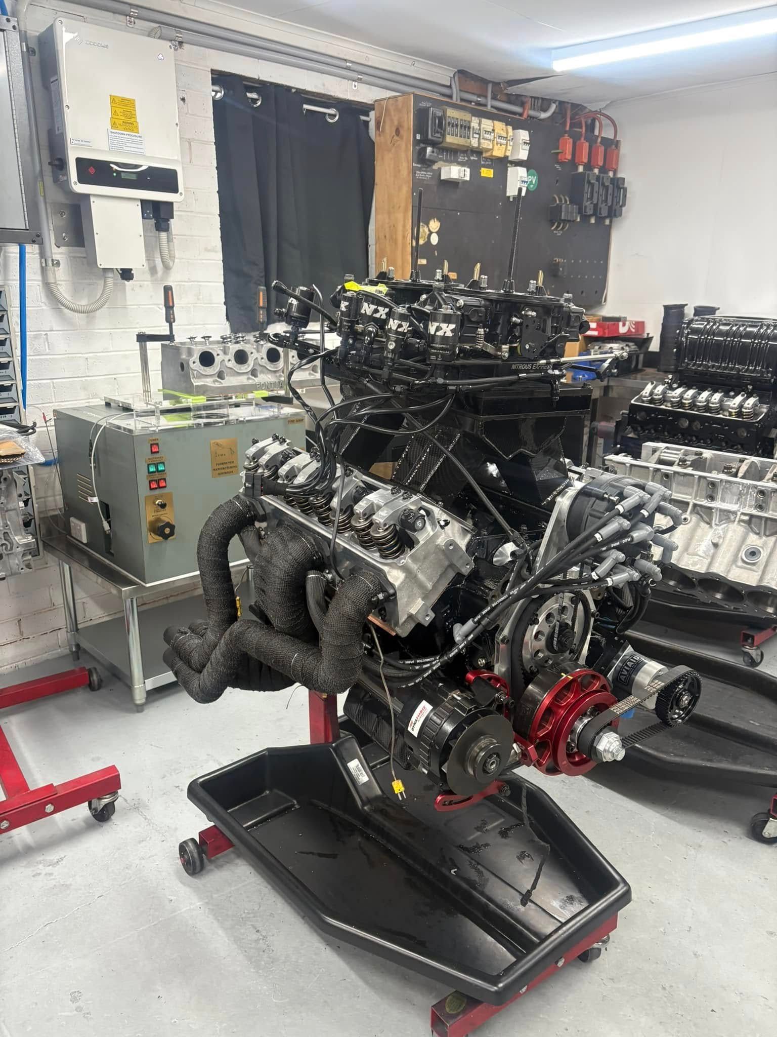 A large engine is sitting on a stand in a garage.