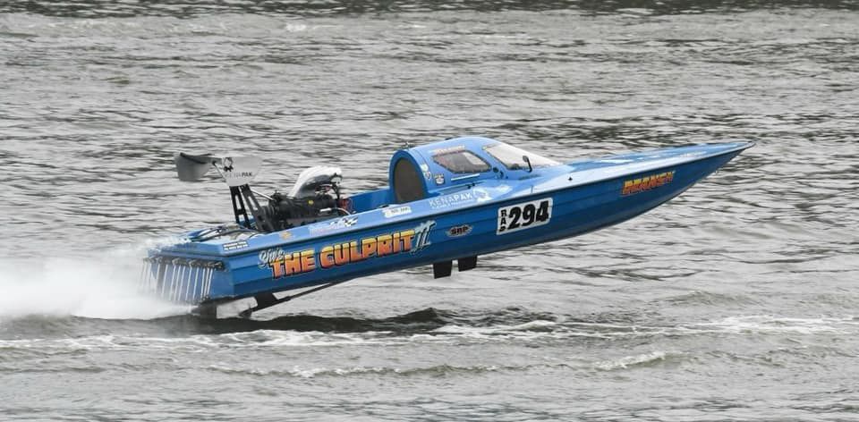 A blue boat is floating on top of a body of water.