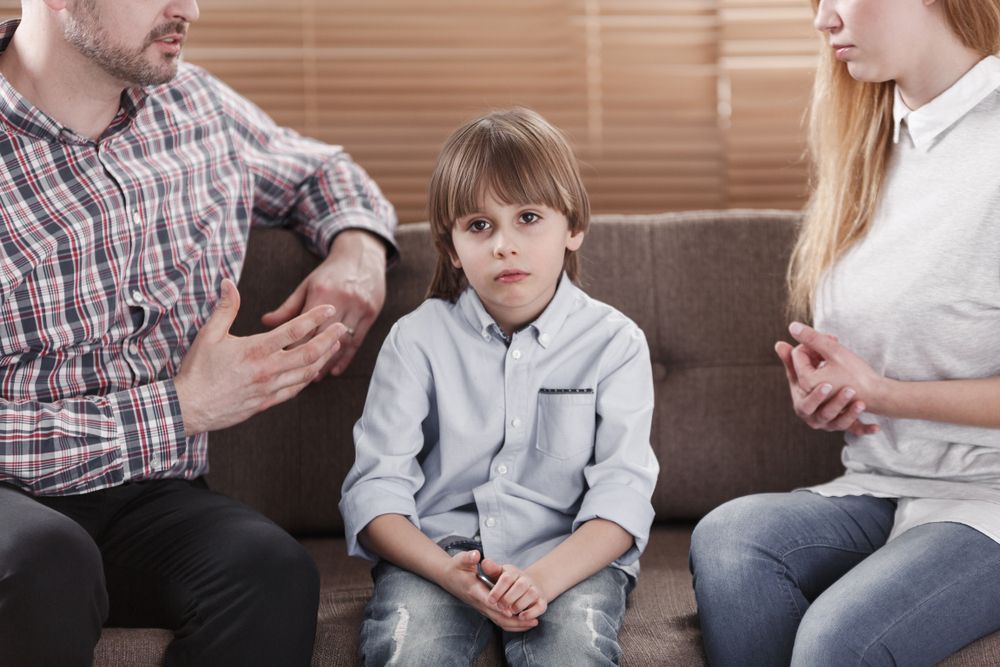 A man and a woman are sitting on a couch with a child.
