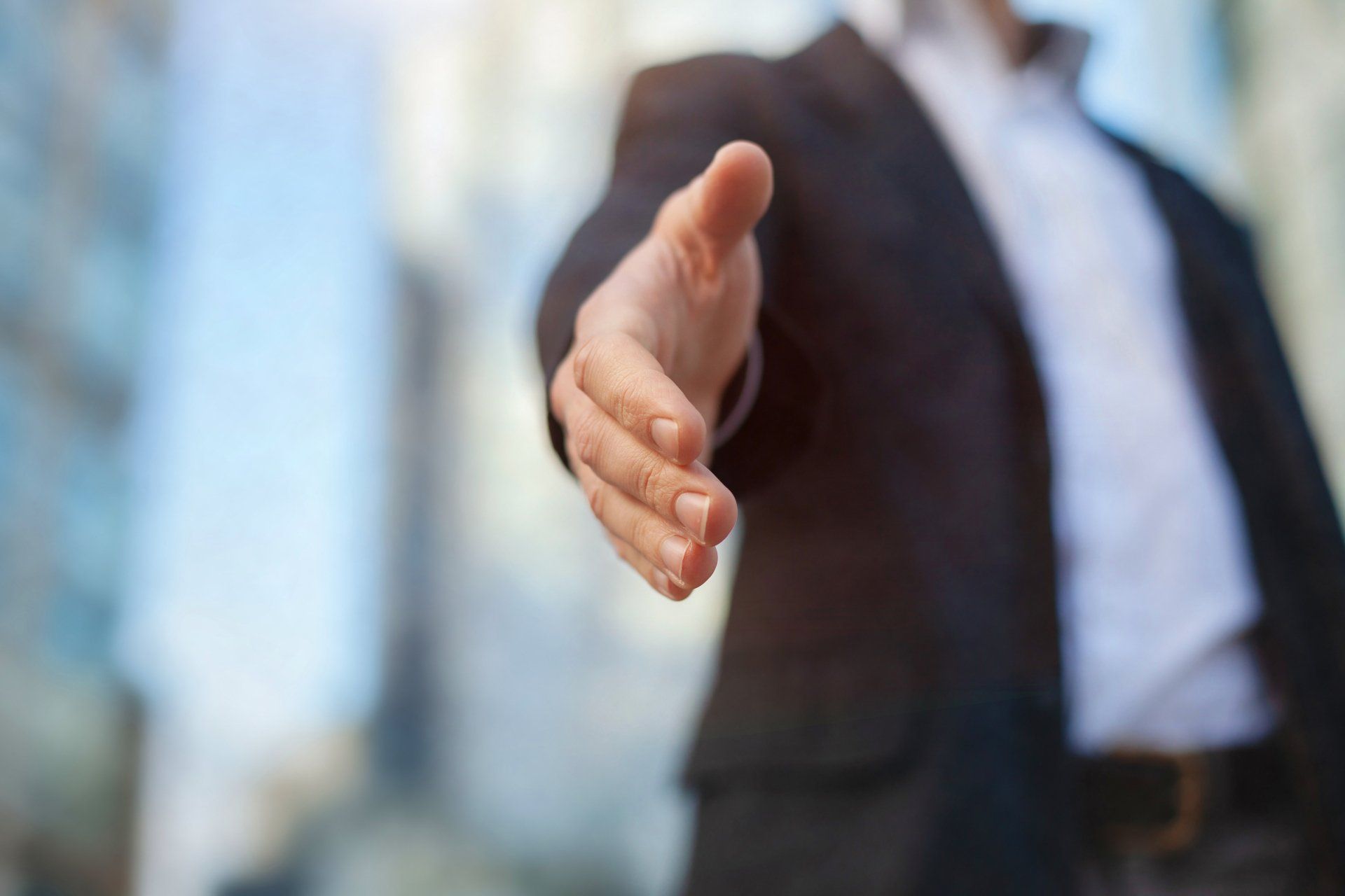 A man in a suit is reaching out his hand to shake someone 's hand.