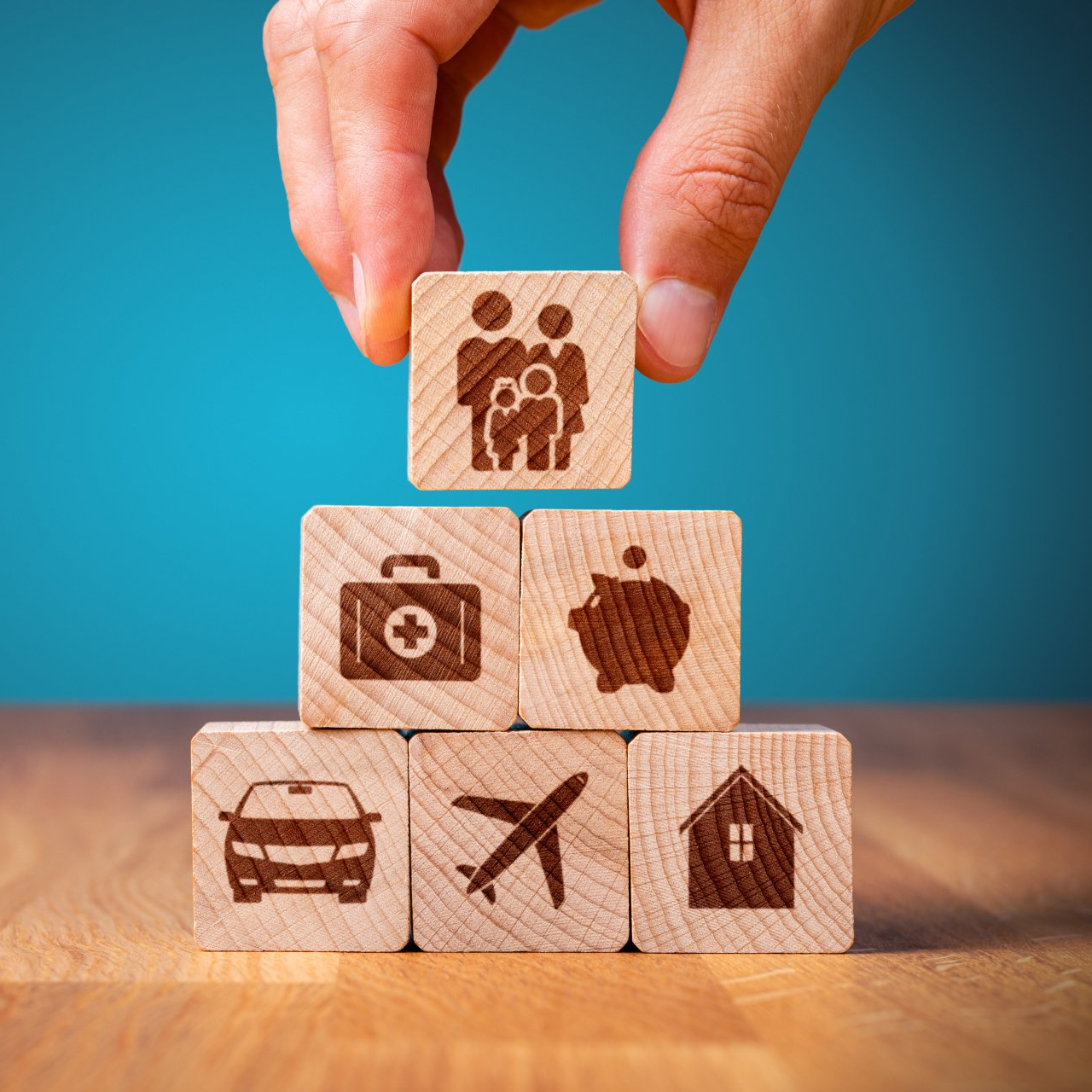 A person is stacking wooden blocks with icons on them.