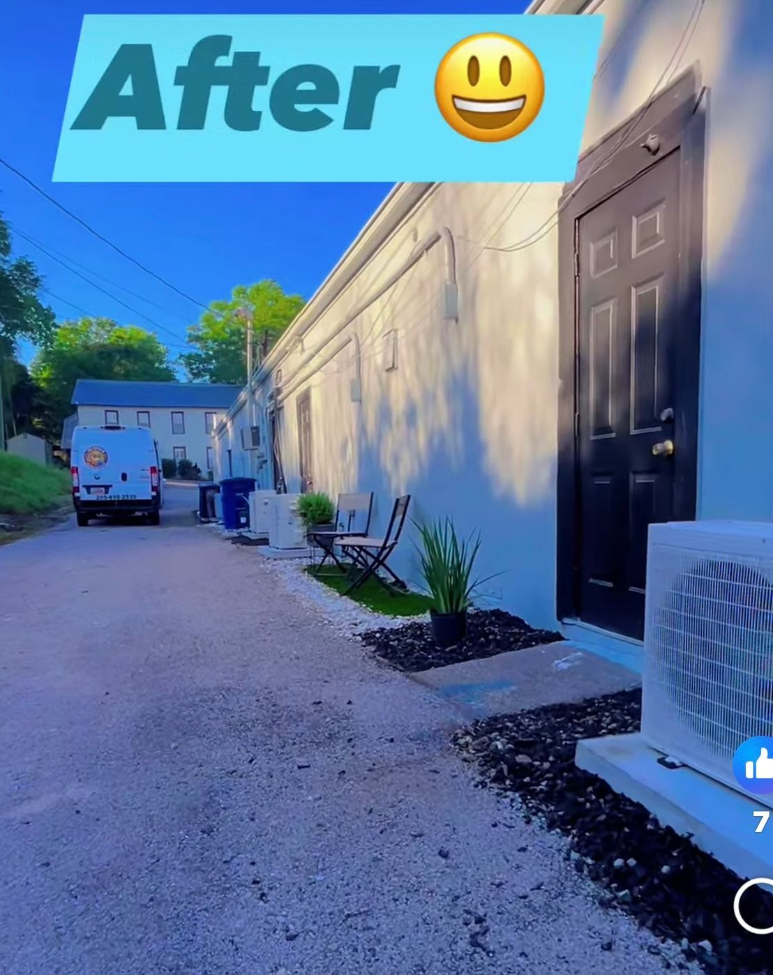 A freshly painted white building with a black door. Landscaping in front. Alley view.