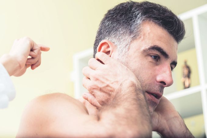 Un uomo si sta facendo visitare il collo da un medico.