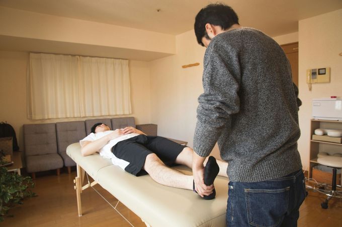 Un uomo è in piedi accanto a un uomo sdraiato su un tavolo.