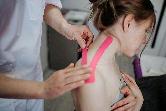 Una donna si sta sottoponendo al nastro kinesiologico sul collo.