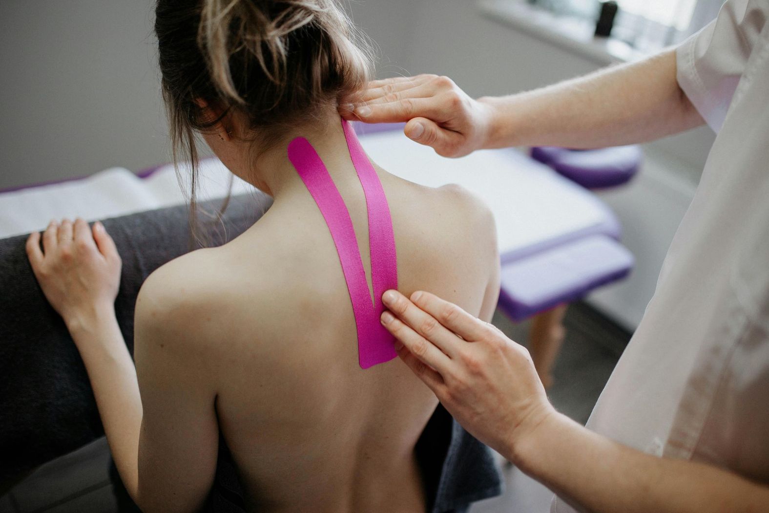 Una donna riceve un massaggio con il kinesio tape sulla schiena.