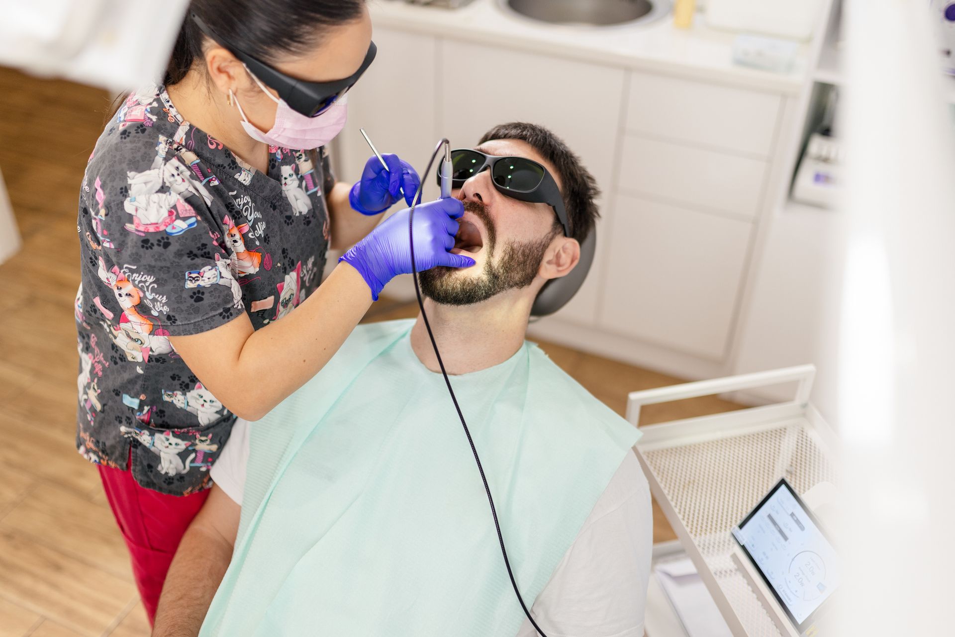 Mature man at dentist office sitting on chair while doctor treats patient with laser. Mature man at dentist office sitting on chair while doctor treats patient with laser.