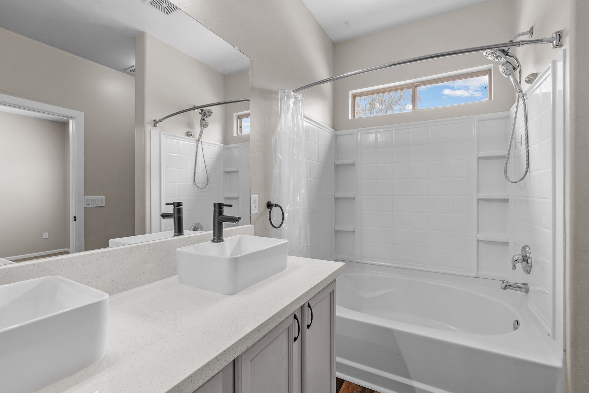 Bathroom with white sink, tub, and tile. Neutral walls and a window.