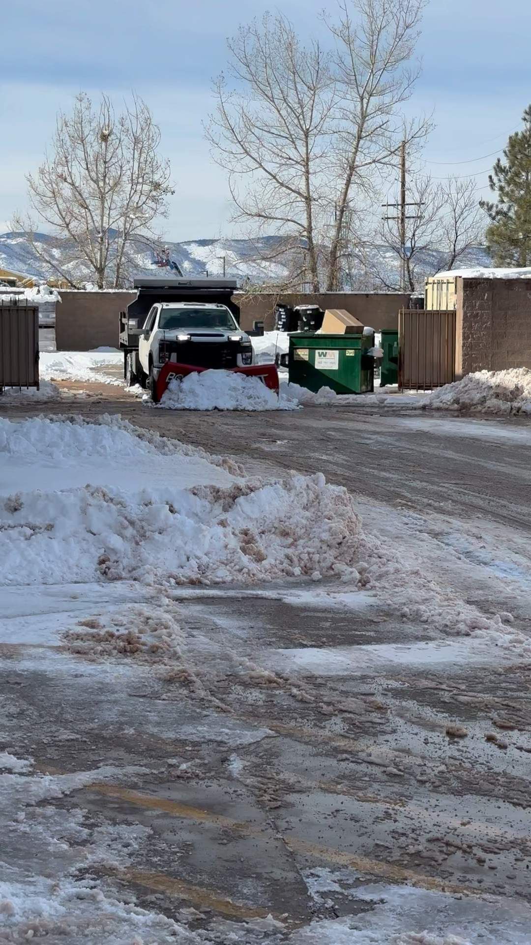 White truck with red snowplow clearing snow on a snowy road.