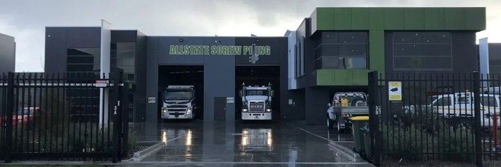 A large warehouse with several trucks parked in front.