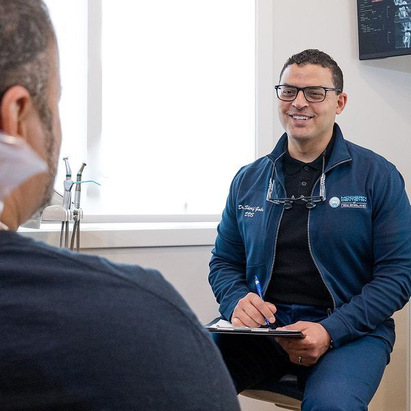 Dr. Gabr talking to a patient who is laying in the dentist's chair