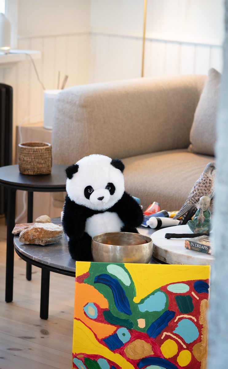 A stuffed panda bear is sitting on a table in a living room.