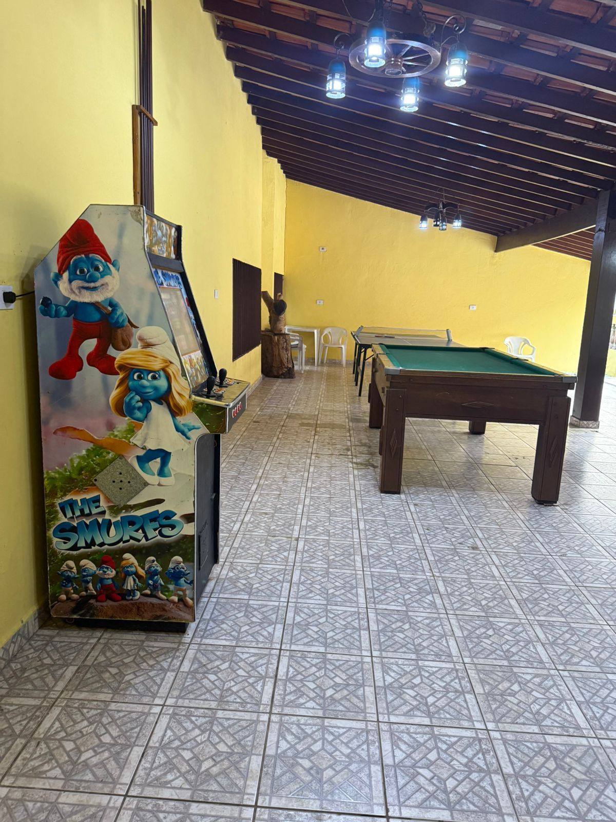 Jogo de fliperama, mesa de sinuca em uma sala de jogos interna. Paredes amarelas.