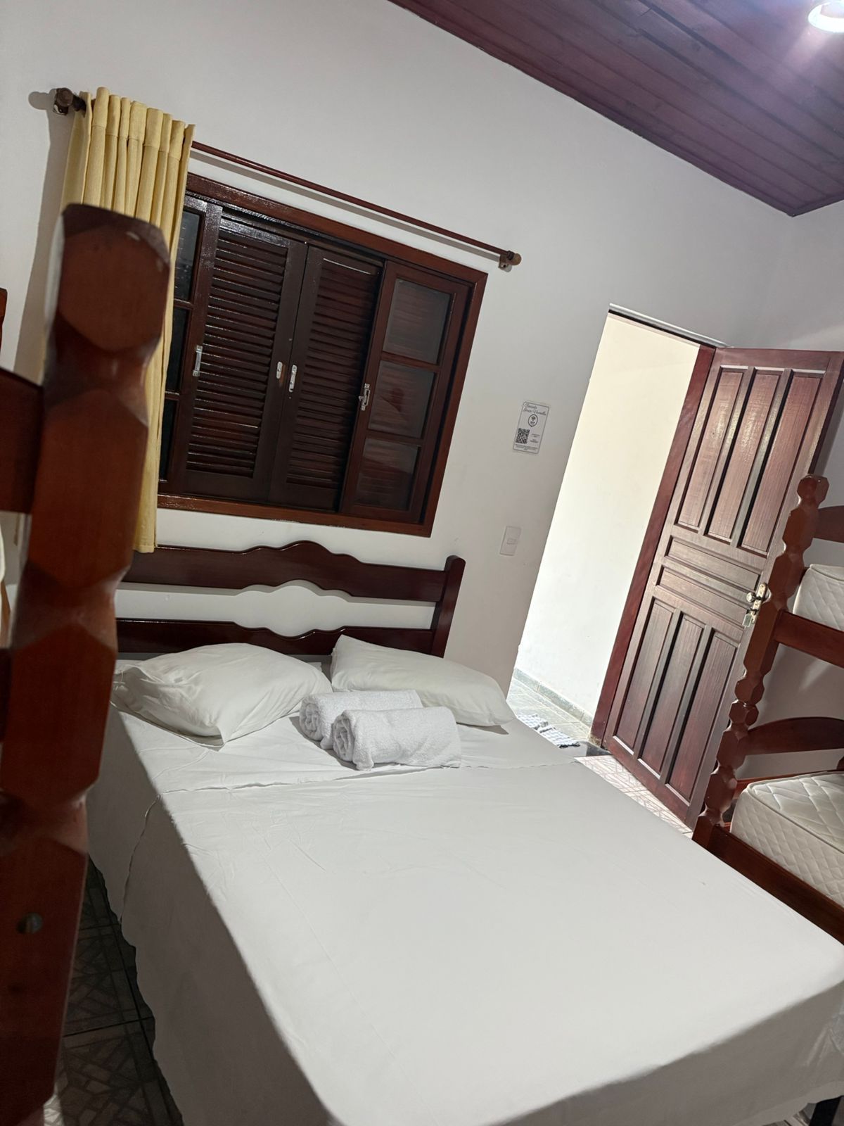 Quarto com uma cama, beliches, uma janela com persianas fechadas e uma porta fechada.