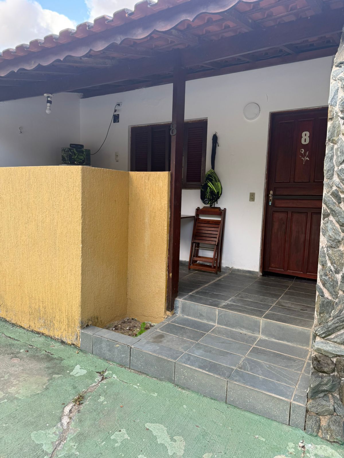 Prédio amarelo e branco com uma porta de madeira escura (rotulada 