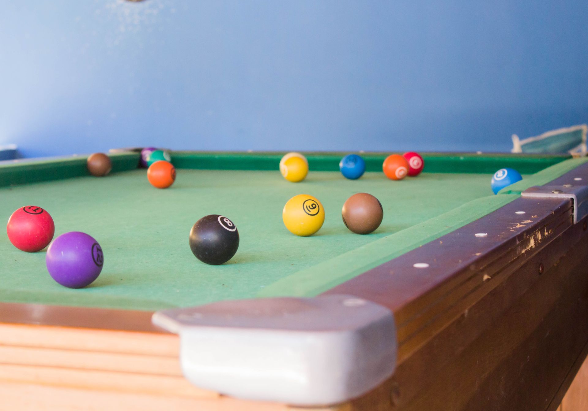 Mesa de sinuca com bolas coloridas espalhadas pelo feltro verde.
