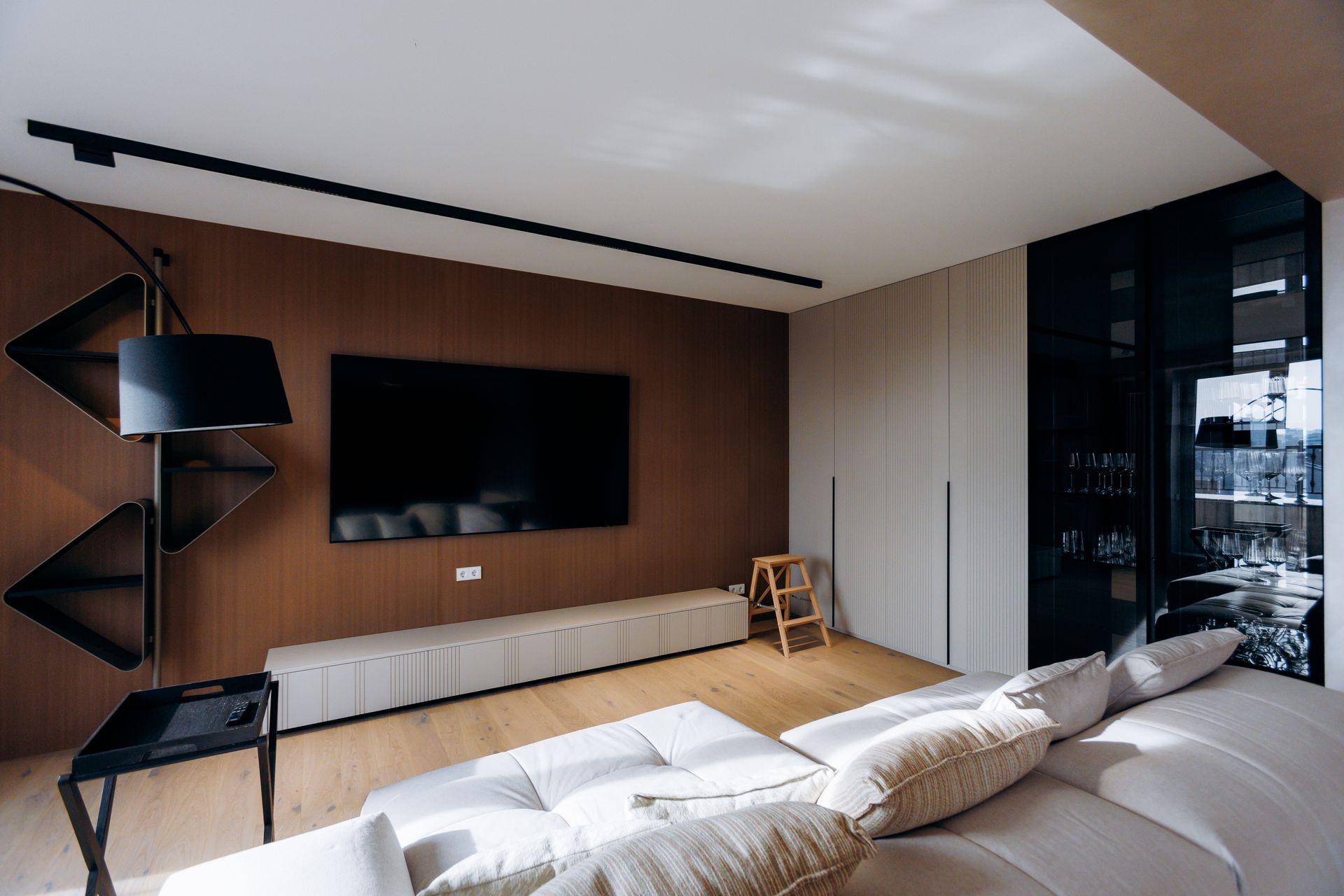 Modern living room with a large TV, built-in storage, and a sectional sofa.