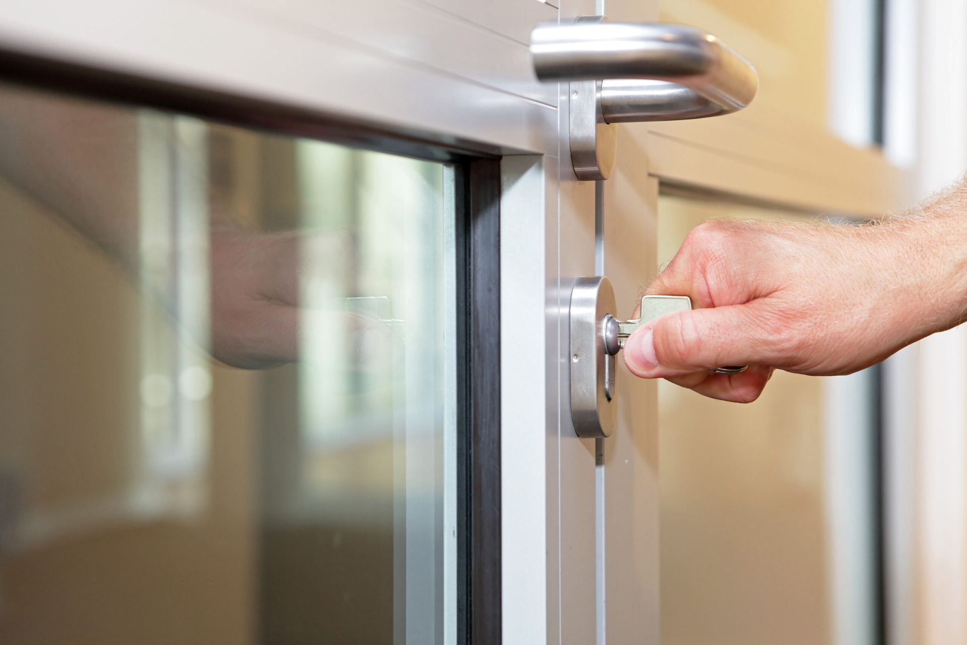 Hand turning a key in a glass door lock