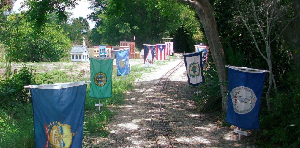 A row of flags hanging from trees on a dirt road