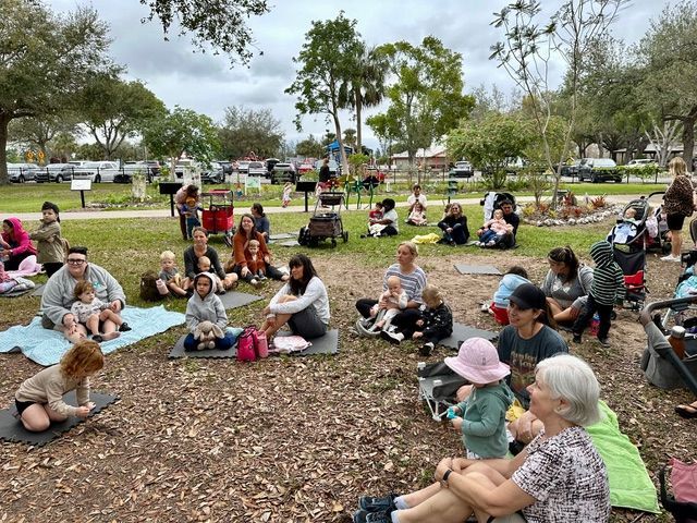 A group of people are sitting on the ground in a park.