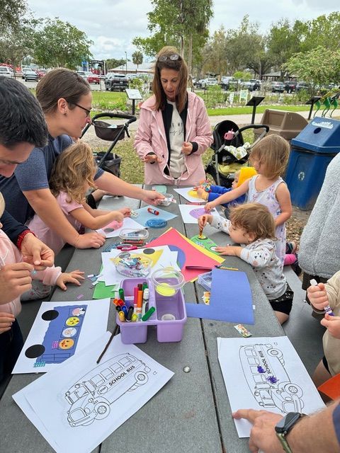 A group of children are sitting at a picnic table making crafts