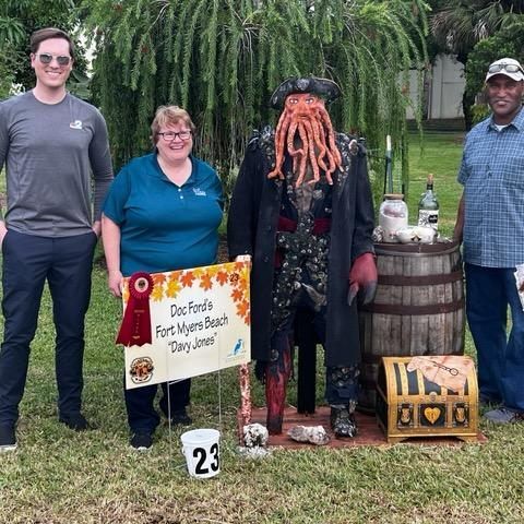 A group of people standing next to a pirate statue holding a sign.