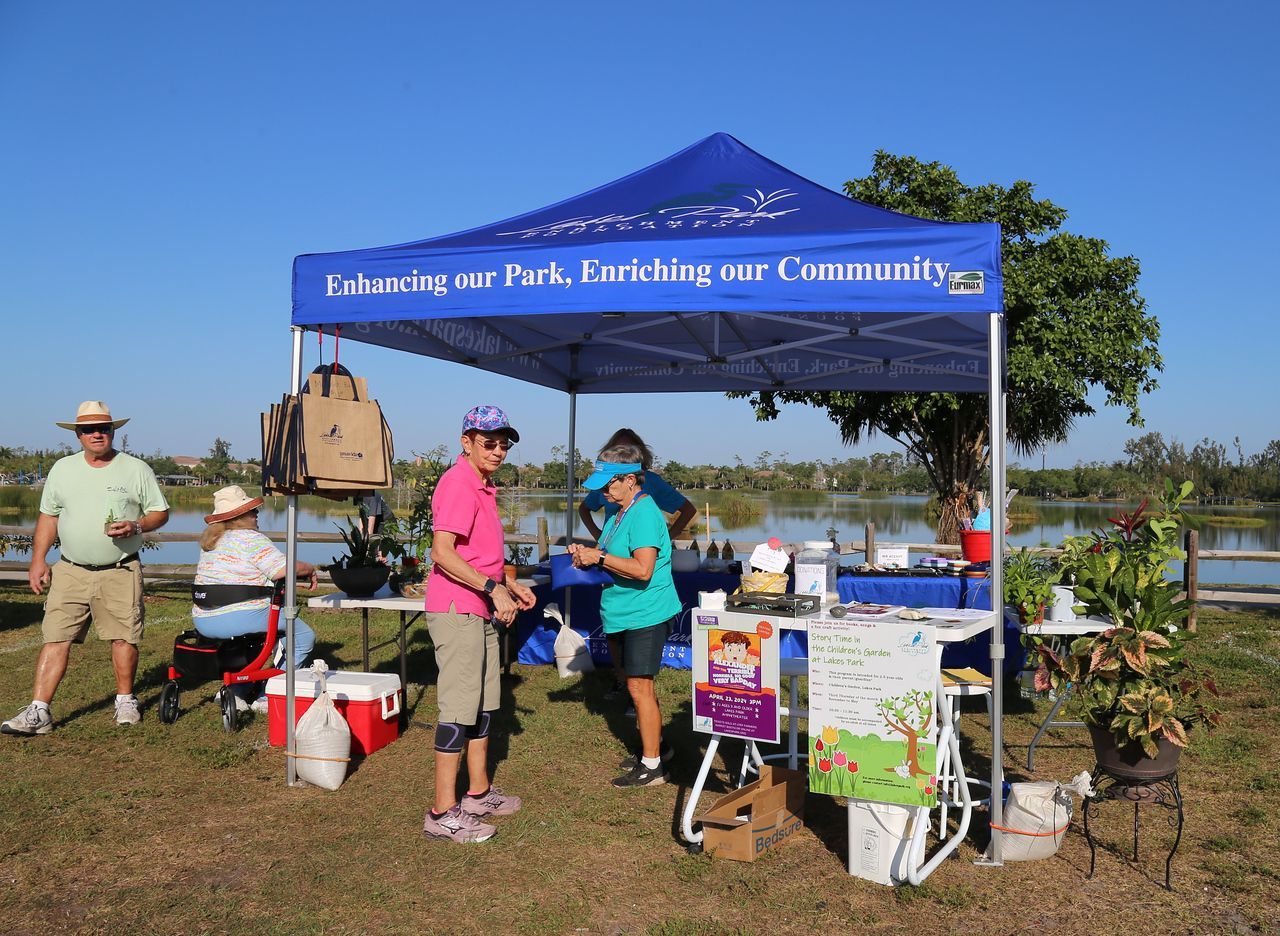 A group of people are standing under a blue tent that says lakeside park tarnishing our community