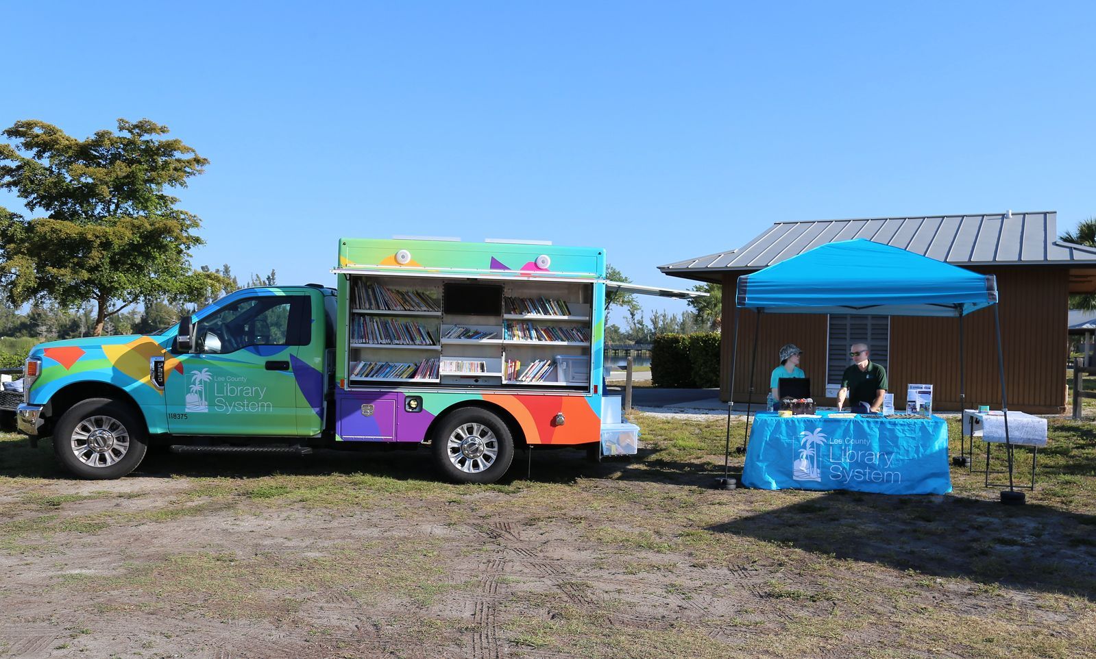 A colorful truck is parked next to a blue tent in a field.
