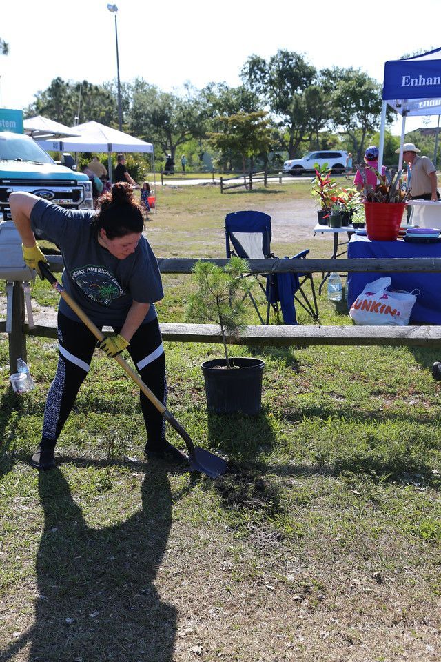 A woman is digging in the grass with a shovel.