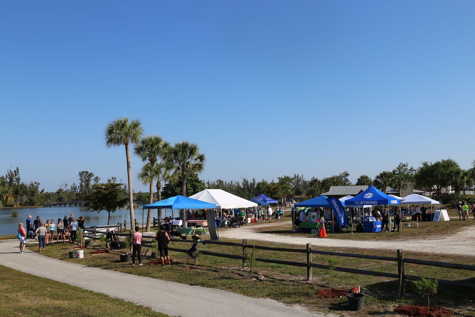A group of people are gathered in a park near a lake.