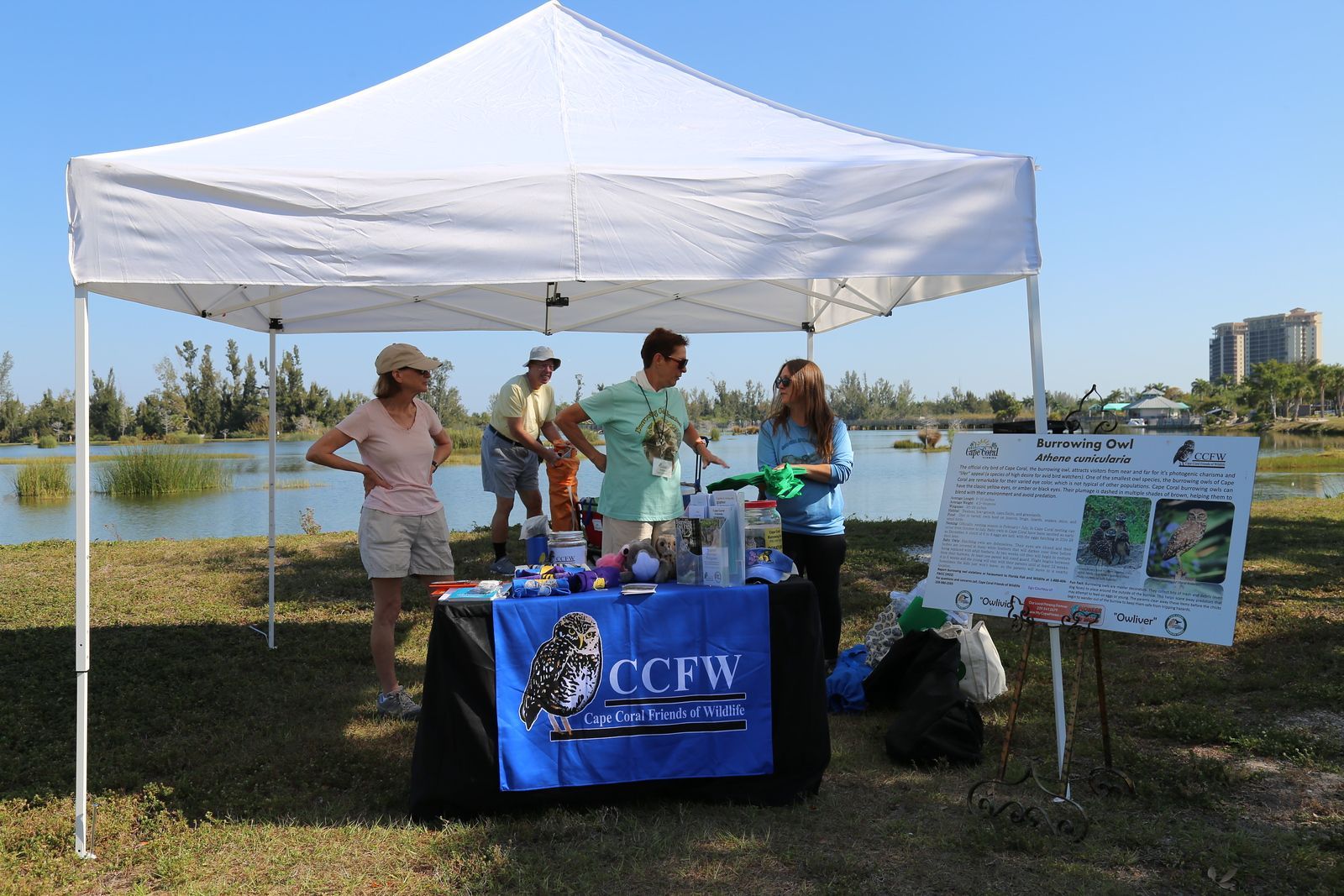 A group of people are standing around a table under a tent.