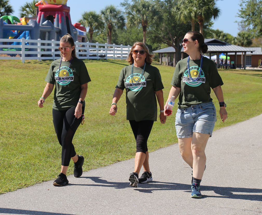 Three women are walking down a path with a bouncy house in the background