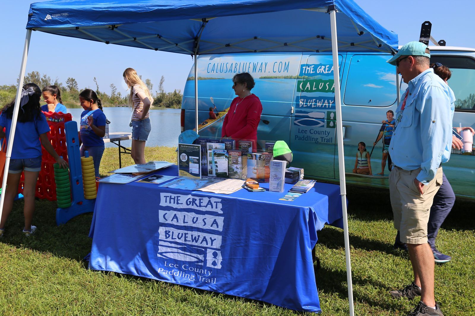 A group of people are standing around a table under a tent.