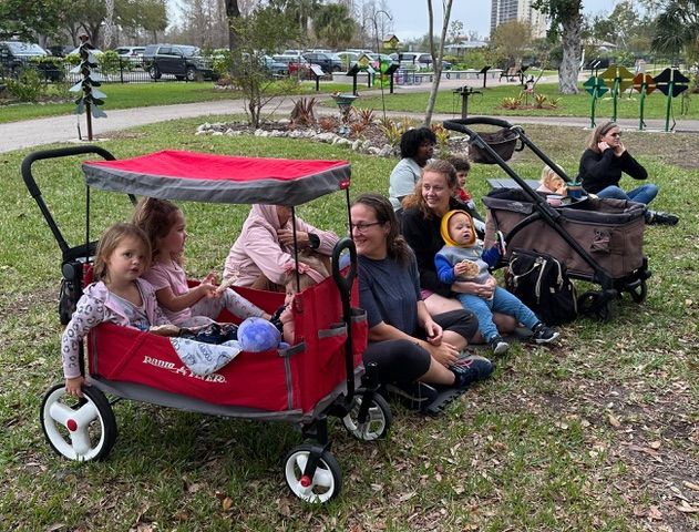 A group of people are sitting in wagons in a park.