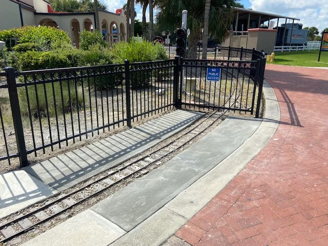 A black fence surrounds a small train track