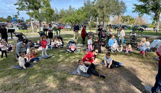A group of people are sitting on the grass in a park.