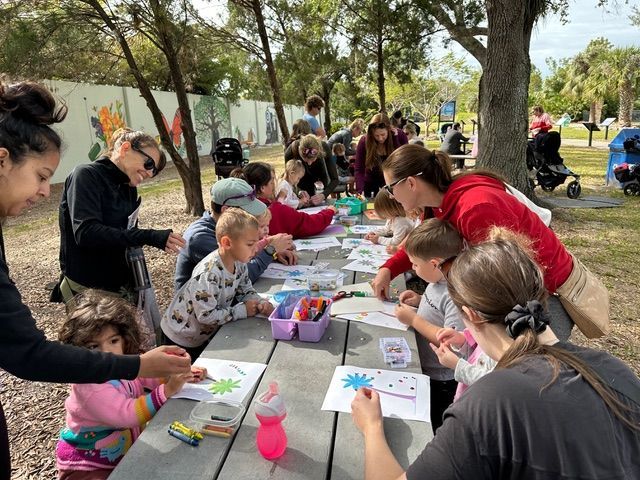 A group of people are sitting at a picnic table in a park.