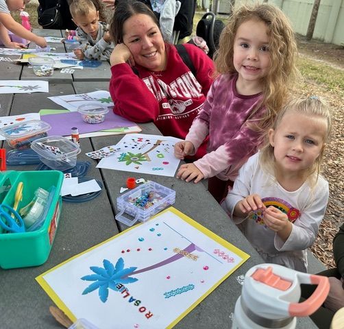 A group of children are sitting around a table with a sign that says rosaline on it