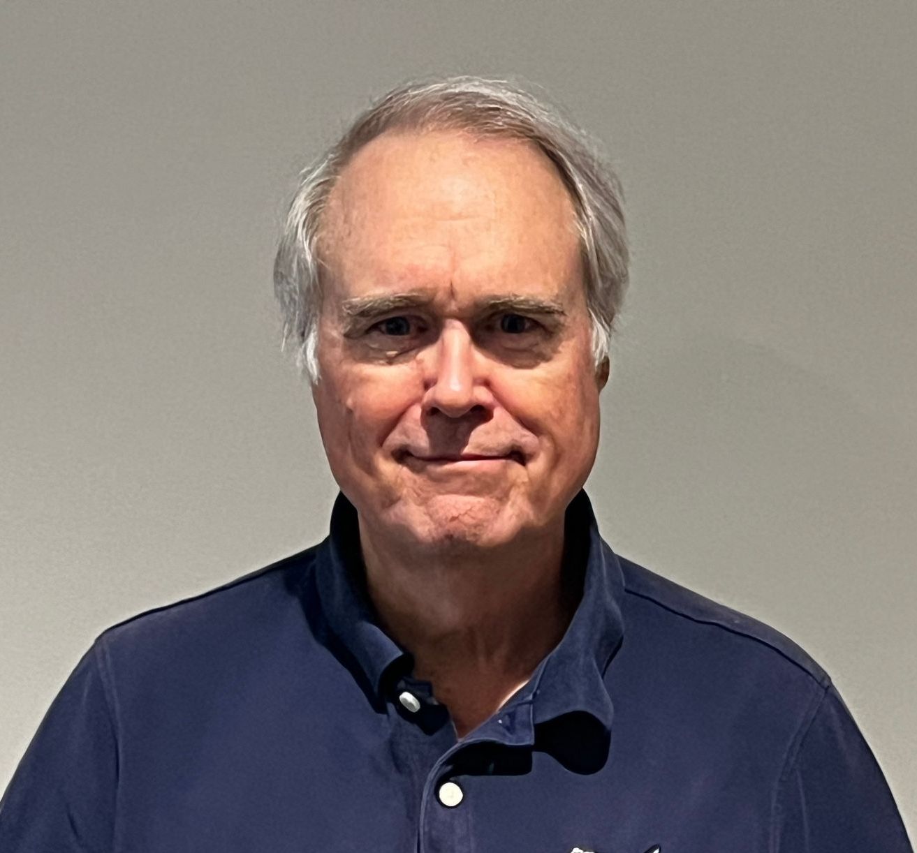 A man in a blue shirt is smiling for the camera.