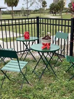 A table and chairs are sitting in the grass in front of a fence.
