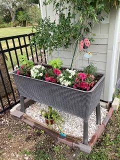 A planter filled with flowers is sitting in front of a house.