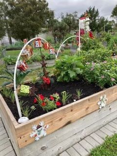 A wooden garden bed filled with lots of plants and flowers.