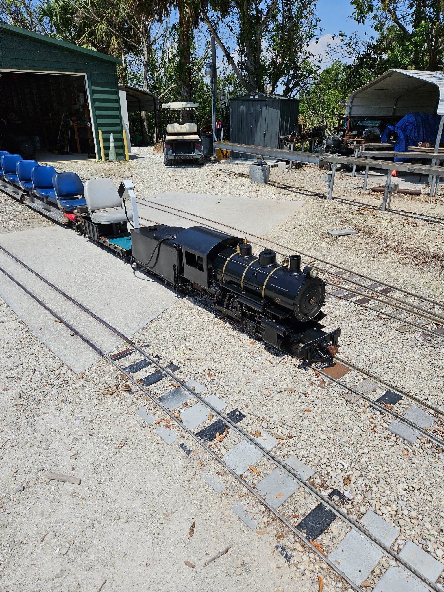 A model train is sitting on top of a gravel track.