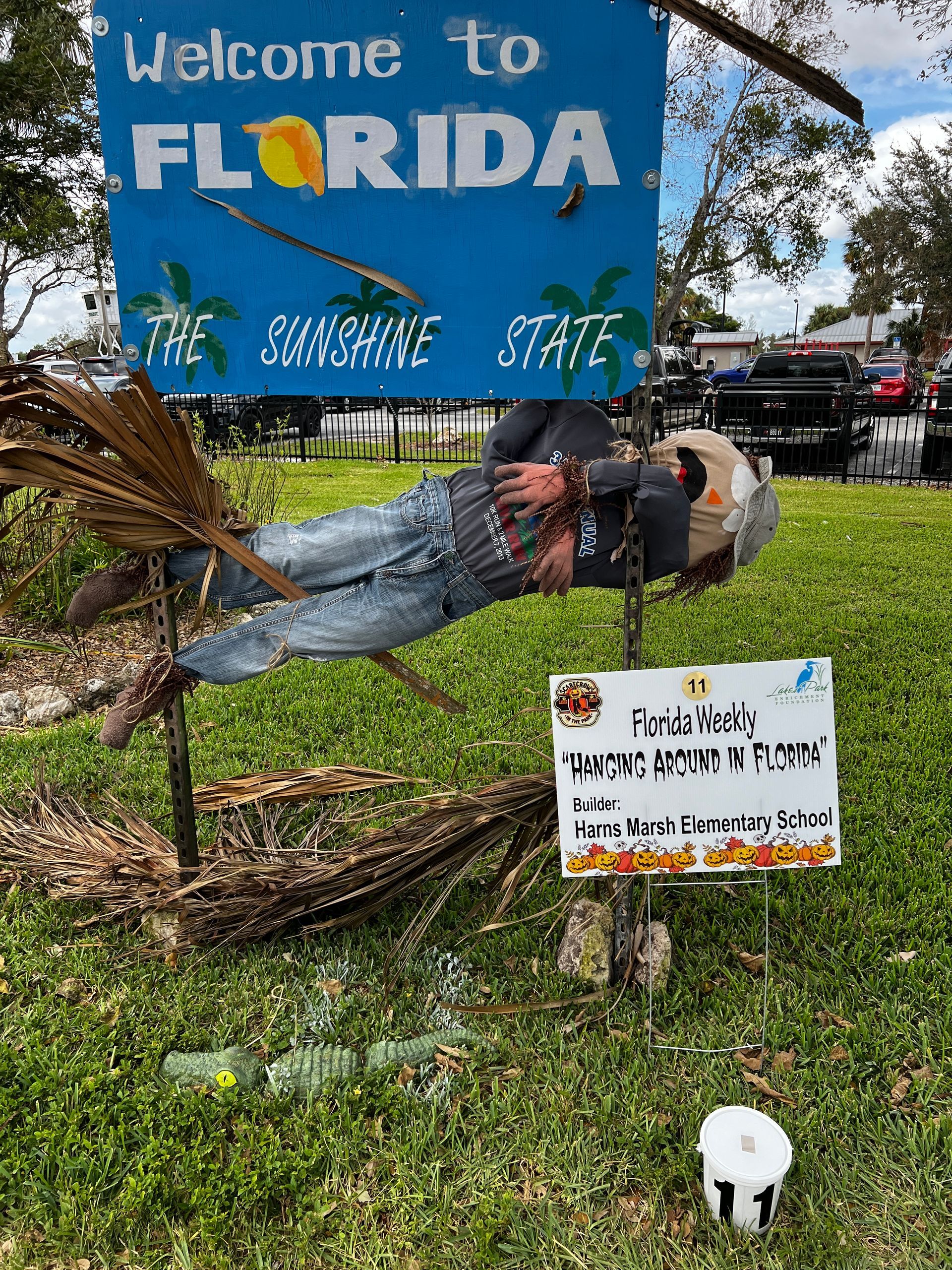A scarecrow is laying in front of a welcome to florida sign.