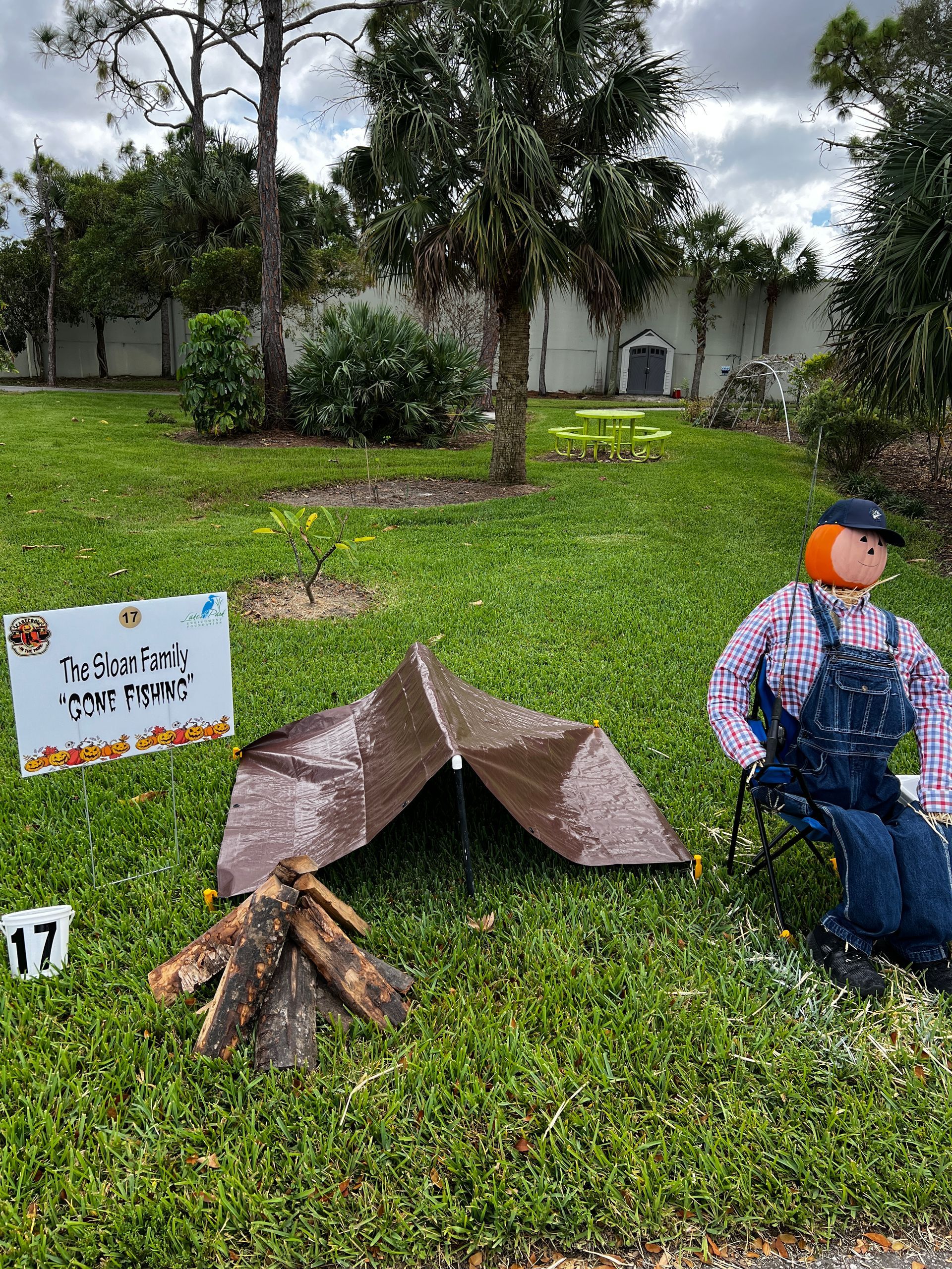 A scarecrow is sitting in a chair in front of a tent.