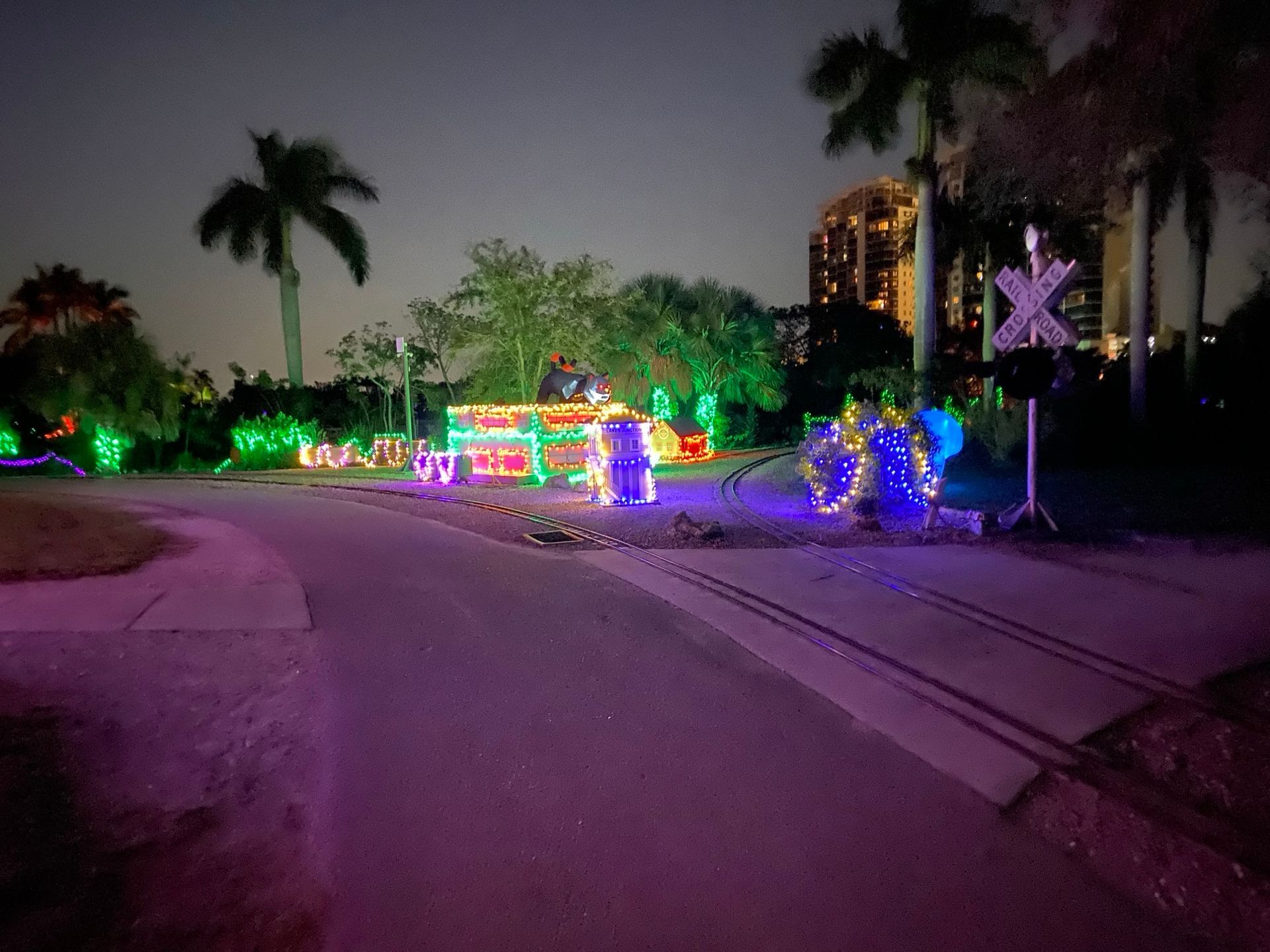 A train track is lit up with christmas lights at night.