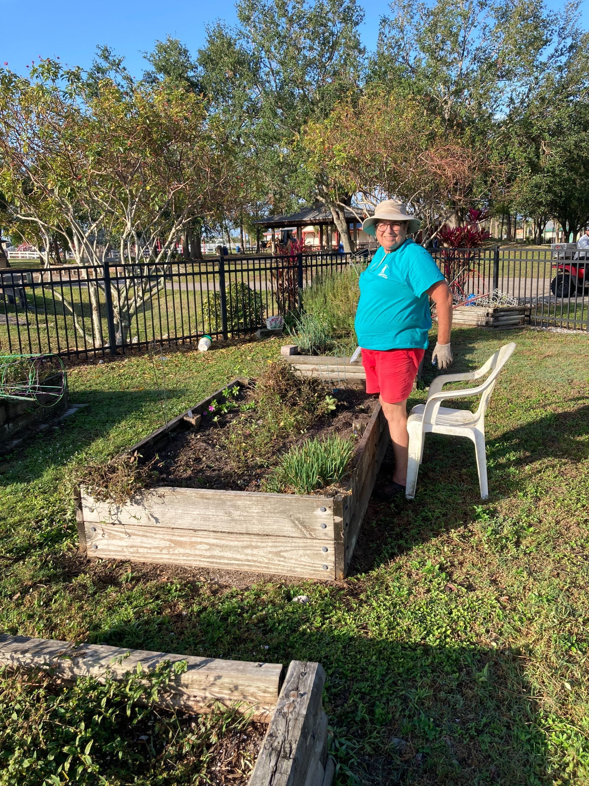 A man is standing next to a chair in a garden.