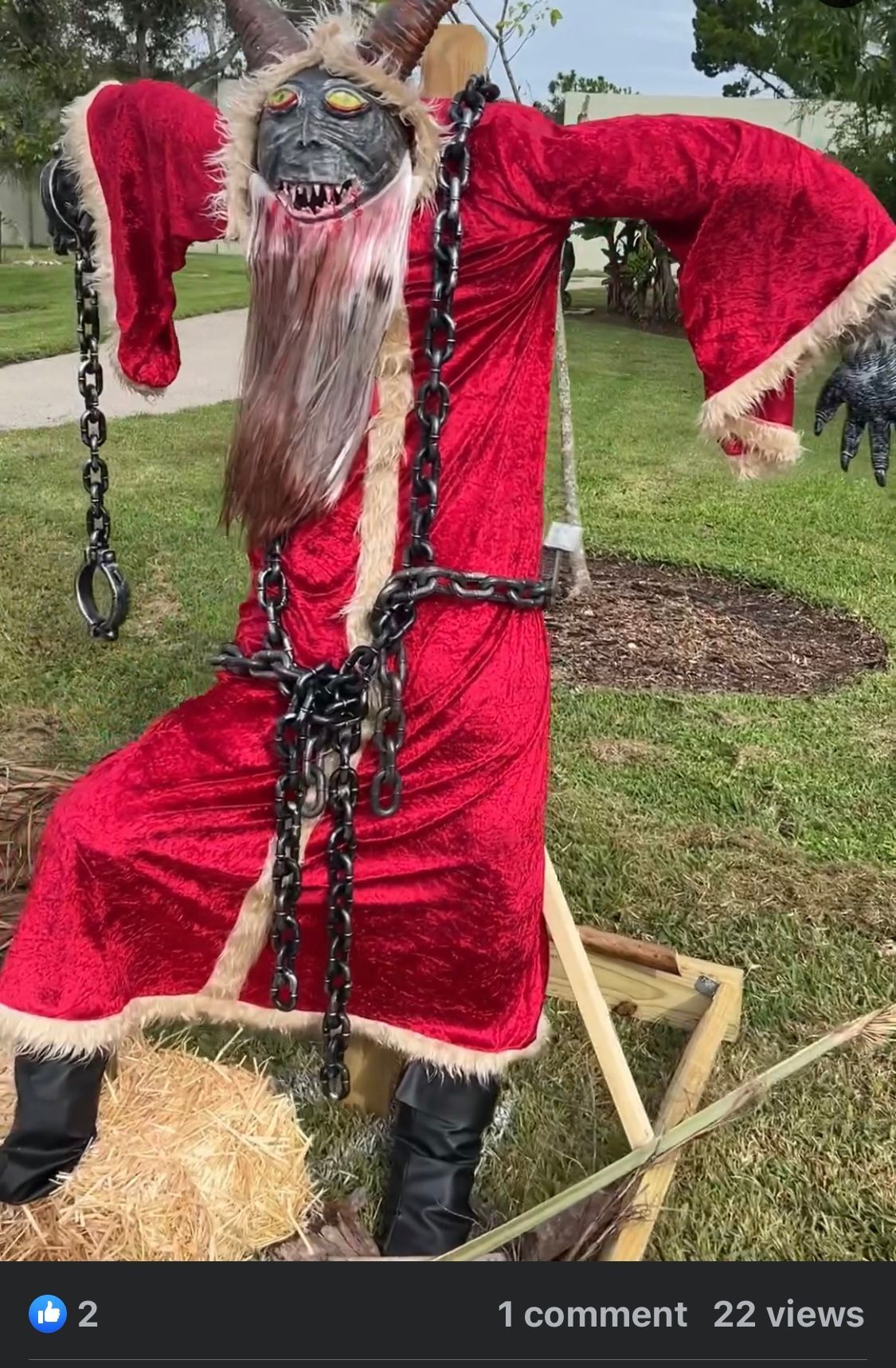 A scarecrow dressed as santa claus is chained to a bale of hay.