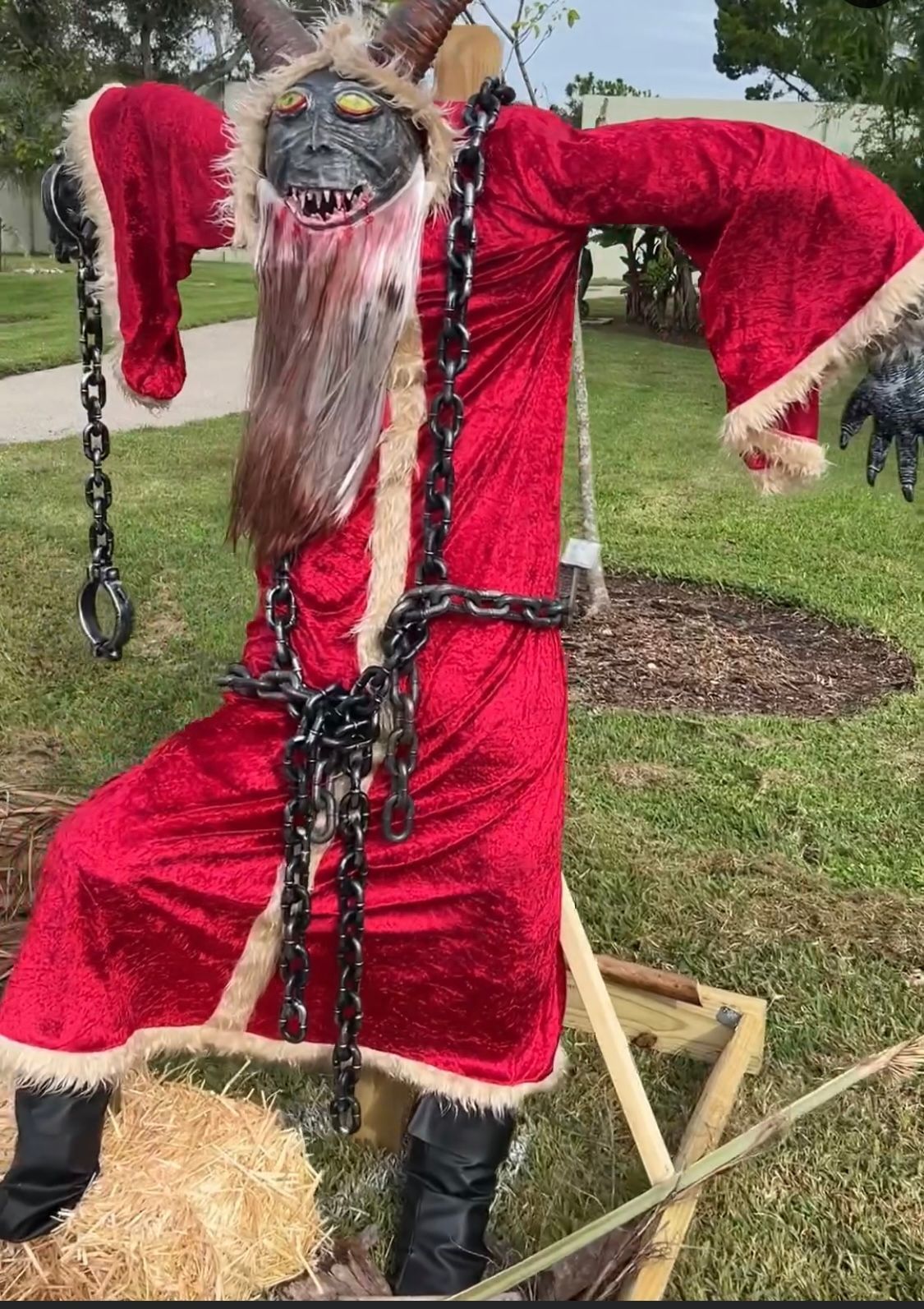 A scarecrow dressed as santa claus with chains around his neck